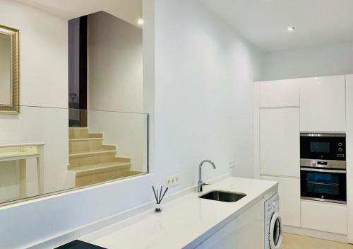 a white kitchen with a sink and a mirror at Stunning Duplex in Capistrano Playa, Nerja in Nerja