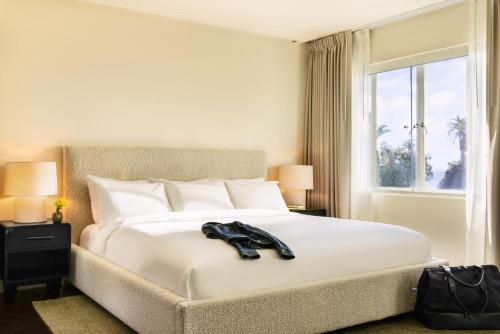 a large white bed with a pair of shoes on it at Sonder The Beacon in Los Angeles