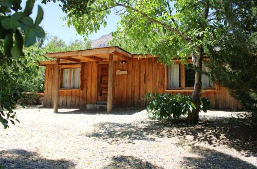 a wooden cabin with a tree in front of it at Cabañas La Calchona in Melocotón