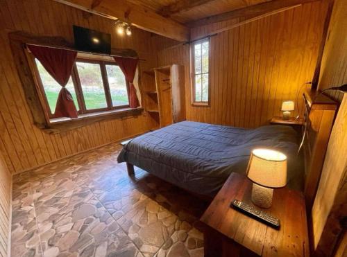 a bedroom with a bed and a table and a window at Cabañas La Calchona in Melocotón