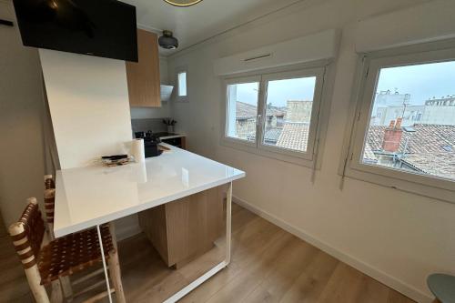 a kitchen with a white counter and two windows at Captivating apartment with all amenities in Bordeaux