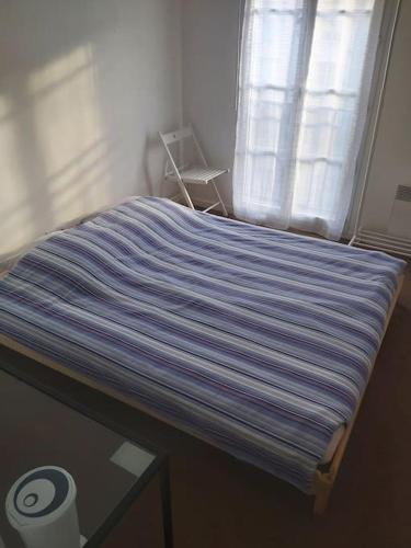 una cama con una manta de rayas azules encima en Apt 3 bedrooms-1km from Disney and Vallée Village en Serris