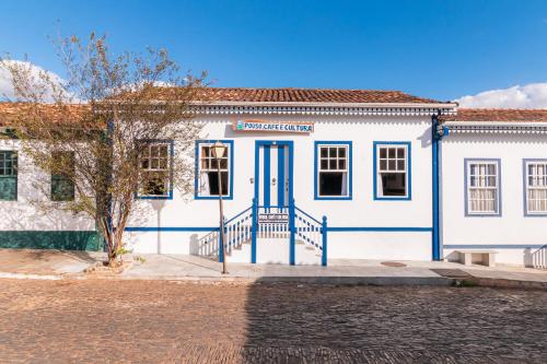 a white building with a blue door on a street at Pouso, Café e Cultura in Pirenópolis