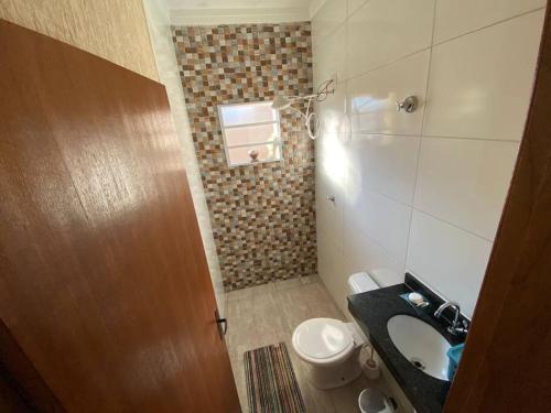 une petite salle de bain avec un lavabo et des toilettes dans l'établissement Casa de cond com piscina e churrasqueira particular, à Itanhaém