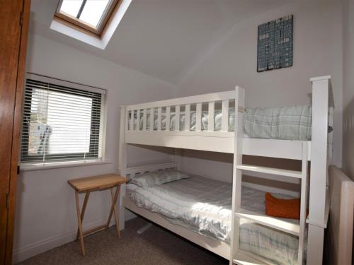 a bedroom with two bunk beds and a table at 3 Bed in Ilfracombe 42432 in Ilfracombe