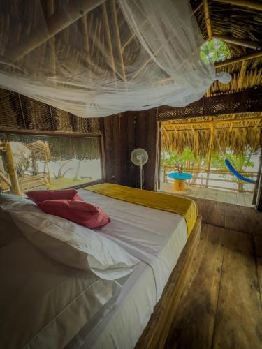 a bedroom with a large bed with a canopy at Los Achiotes Hostal in Palomino