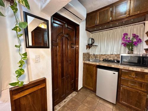 a kitchen with wooden cabinets and a sink and a microwave at CABO BOHEMIA Tropical Garden Studios in Cabo San Lucas