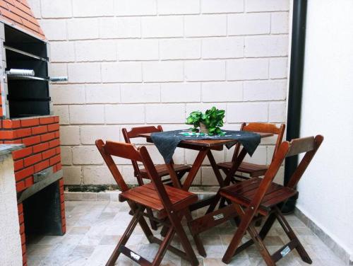 une table avec quatre chaises et une plante dessus dans l'établissement Casa de cond com piscina e churrasqueira particular, à Itanhaém