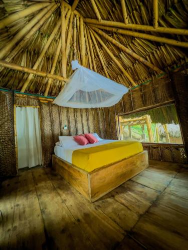 a bedroom with a bed in a straw hut at Los Achiotes Hostal in Palomino