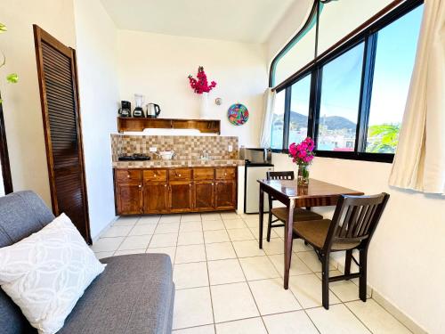 a living room with a table and a kitchen at CABO BOHEMIA Tropical Garden Studios in Cabo San Lucas