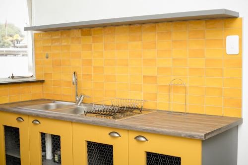 a kitchen with a sink and yellow tiles at Urban Oasis Apartments at Hidas in Windhoek