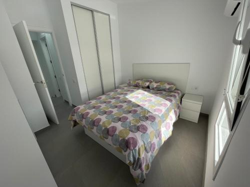 a small bedroom with a bed with a colorful comforter at Isis House in Maspalomas