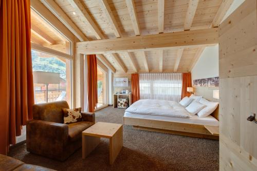 a bedroom with a bed and a chair at Hotel Aristella Swissflair in Zermatt