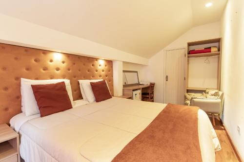 1 dormitorio con 1 cama blanca grande con almohadas rojas en Pousada VHL - Campos do Jordão, en Campos do Jordão