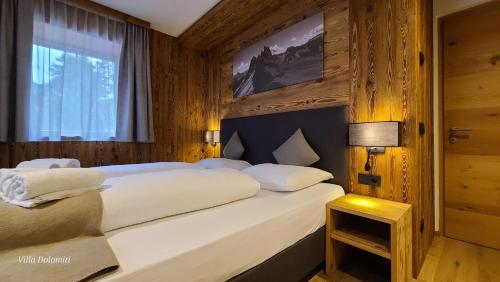 Schlafzimmer mit einem großen weißen Bett und einem Fenster in der Unterkunft Villa Dolomiti in St. Ulrich in Gröden