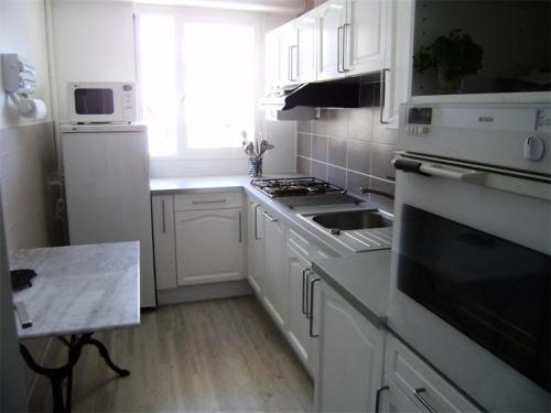 une cuisine avec des armoires blanches et un four à plaques de cuisson dans l'établissement Résidence Casino - Charmant T3 en plein cœur de la station balnéaire du Val-André. MAE-6444, à Pléneuf-Val-André