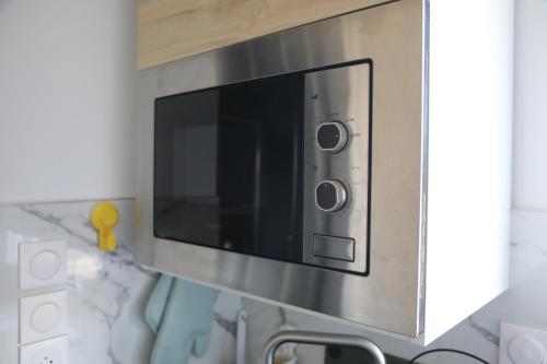 un four à micro-ondes accroché au mur d'une cuisine dans l'établissement Charmant studio en centre-ville, à Mulhouse