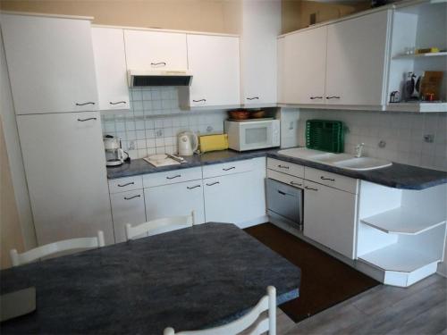 une petite cuisine avec des armoires blanches et une table dans l'établissement Résidence Casino - Spacieux T2, à deux pas de la plage du Val André. MAE-6604, à Pléneuf-Val-André