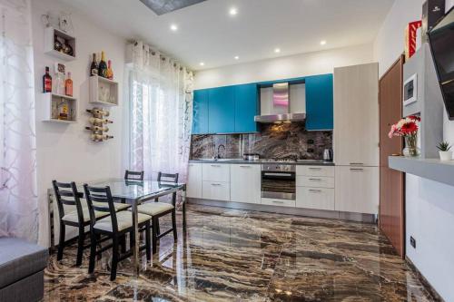 Appartamento Luxury Adri في Talignano: مطبخ مع طاولة وكراسي ودواليب زرقاء