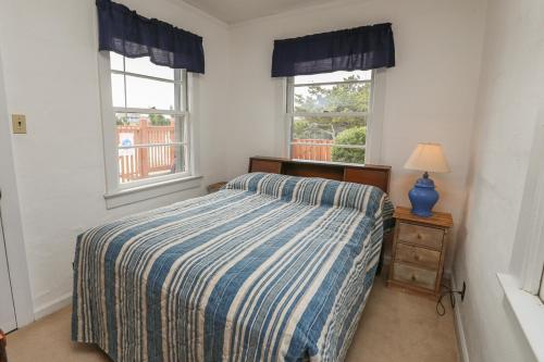 a bedroom with a bed and two windows at Clipper - Oceanfront Outer Banks Home with Private Pool - 5BR/3.5BA in Southern Shores