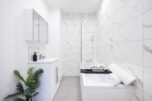 Baño blanco con lavabo y espejo en Brand New Modern Block of Apartments By AV Stays Short Lets London en Croydon
