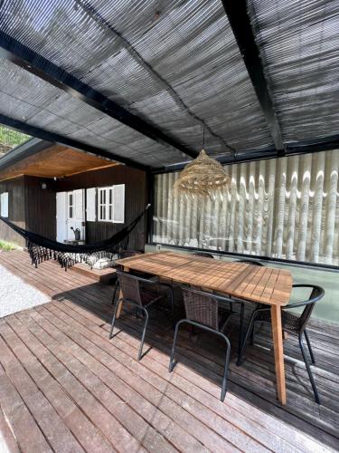a wooden table and chairs on a deck with a hammock at A casa da Lomba in Lomba