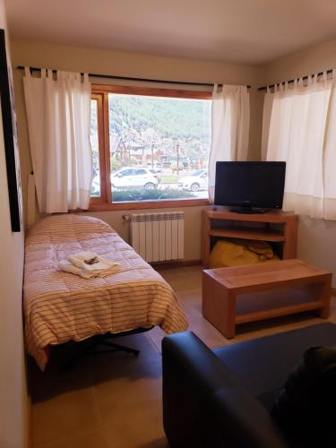 Schlafzimmer mit einem Bett, einem TV und einem Fenster in der Unterkunft Departamento Frente al Lago-San Martin de Los Andes in San Martín de los Andes
