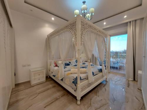 Cama con dosel blanca en un dormitorio con ventana en Andlous inn en Hurghada