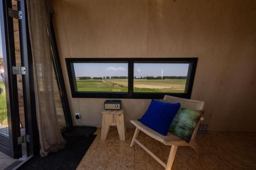 Slapen op de Dijk - Tiny House في كْراخينبورْخْ: غرفة بها نافذة وكرسي وطاولة