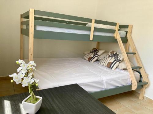 1 dormitorio con 2 literas y un jarrón con flores en Logement Charme vanillé - Gosier - 2 chambres - Piscine - Wifi - Parking en Le Gosier