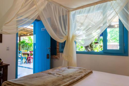 a bedroom with a canopy bed with blue windows at Suite DAVI - Guest House Guaiu in Santa Cruz Cabrália