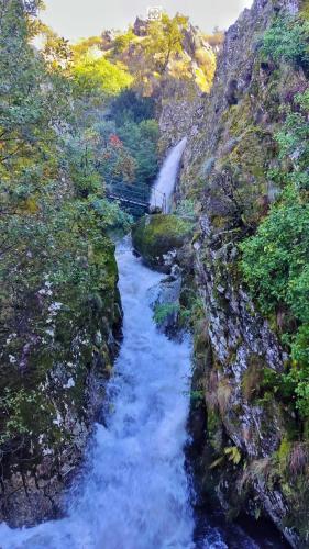 a river running through a canyon with a bridge at Chalé Zimbro, Serra da Estrela, Penhas da Saúde in Penhas da Saúde