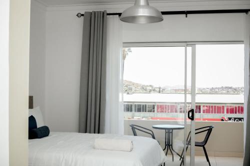 a bedroom with a bed and a table and a window at Hidas serviced apartments in Windhoek