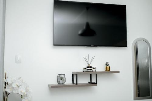 a tv hanging on a white wall with a table at Hidas serviced apartments in Windhoek