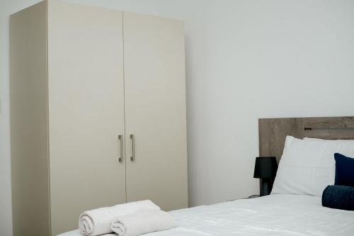 a bedroom with white cabinets and a bed with towels at Hidas serviced apartments in Windhoek