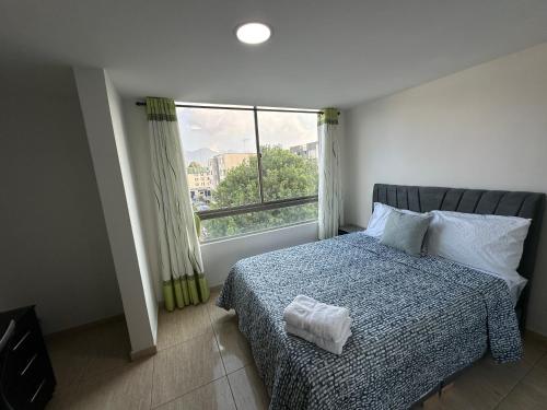 a bedroom with a bed and a large window at APARTAMENTO AMOBLADO CERCA A METROPOLIS in Bogotá