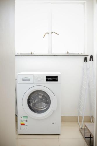 a white washer and dryer in a white laundry room at Hidas serviced apartments in Windhoek