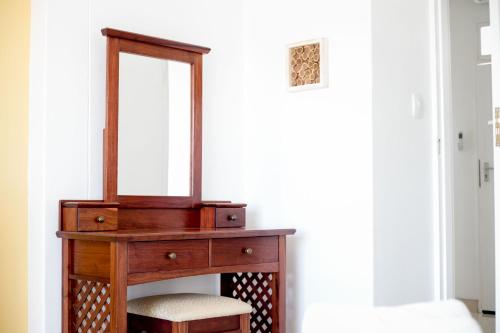 a wooden dressing table with a mirror and two stools at Hidas serviced apartments in Windhoek
