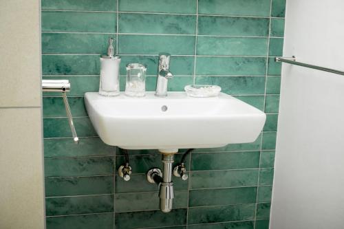 a white sink in a green tiled bathroom at Hidas serviced apartments in Windhoek