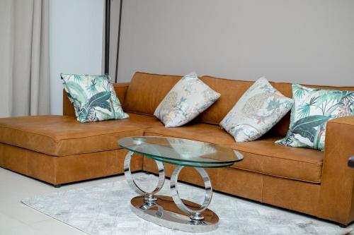 a brown couch with pillows and a glass table at Hidas serviced apartments in Windhoek