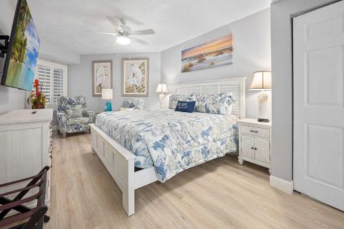 a bedroom with a bed and two chairs and a ceiling fan at Luxury Beach Villa Wyndham Ocean Walk Resort in Daytona Beach