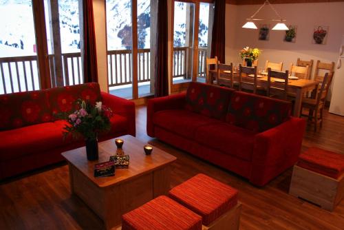 a living room with two red couches and a table at Chalet des Neiges : La Cime Des Arcs in Arc 2000