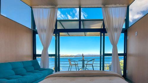 a bedroom with a large window with a couch and a table at Cabañas los Sauces in Tota