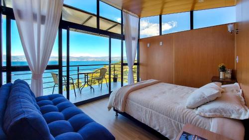 a bedroom with a bed and a couch and a balcony at Cabañas los Sauces in Tota