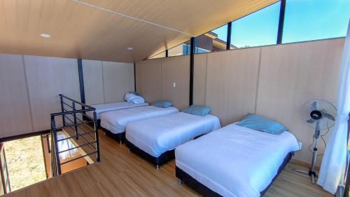 three beds in a room with a window at Cabañas los Sauces in Tota