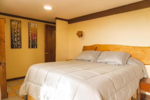 a bedroom with a large bed with white sheets at Cabañas El Bosque in Maitencillo