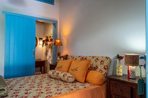 um quarto com uma cama com almofadas laranja e uma porta azul em Suite LIAM - Guest House Guaiu em Santa Cruz Cabrália