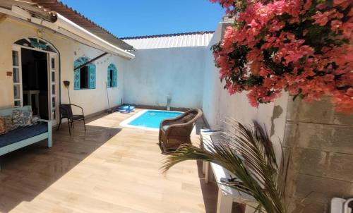 um pátio com uma piscina, uma cadeira e flores em Casa 3 quartos 2 banheiros patio gramado fechado com piscina em Guarapari