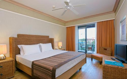 a bedroom with a large bed and a television at Lykia World Links Golf Antalya in Denizyaka