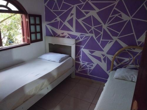 Habitación con 2 camas y pared púrpura. en Guarus house plaza shopping, en Campos dos Goytacazes